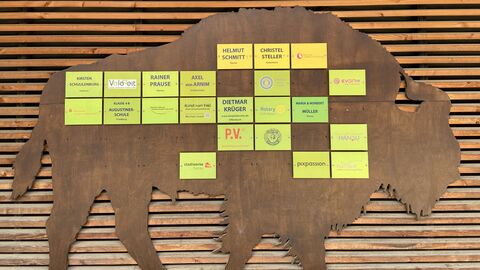 Auf einem Wisent aus Holz sind die Logos der Spender angebracht