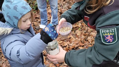 Försterin bastelt gemeinsam mit Kind einen Futterzapfen