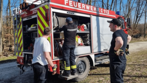 Entladen der Gerätschaften Auf dem Foto sehen sie mehrere Personen die vor einem Feuerwehrauto stehen