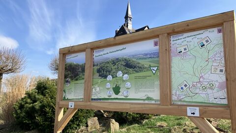 Auf dem Foto sehen Sie eine Infotafel, die über den neuen Wanderweg informiert. 