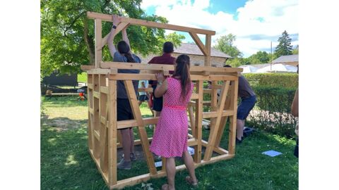 Mehrere Personen bauen ein Miniaturfachwerkhaus auf