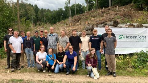Pflanzaktion im Revier Cornberg Die Gruppe der Helferinnen und Helfer der PFlanzaktion steht vor der Fläche und einem HessenForst-Banner