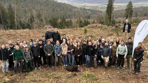 Die Gruppe der freiwilligen Helfer steht auf der Pflanzfläche und blickt den Berachter an. 